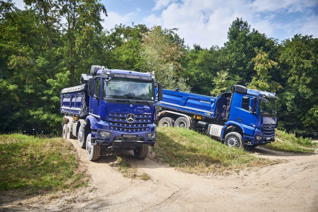 Zwei Baufahrzeuge von Mercedes-Benz Trucks beim Fahren im Gelände