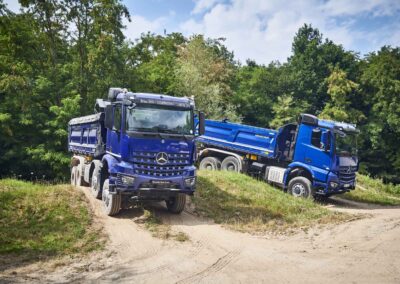 Zwei Baufahrzeuge von Mercedes-Benz Trucks beim Fahren im Gelände