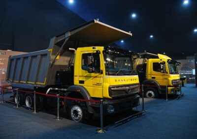 Zwei schwere Baufahrzeuge der Marke Bharat-Benz nebeneinander auf einem Messestand