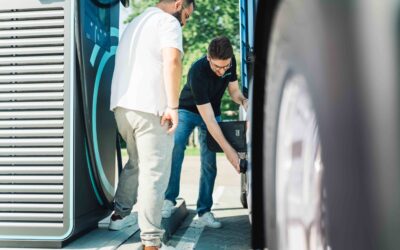 ein Mann steckt einen Ladstecker in einen eActros, geparkt an einer Ladesäule