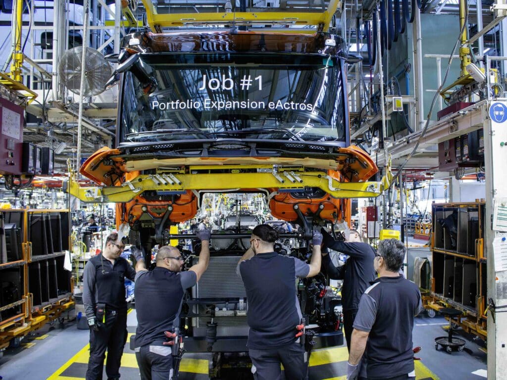 Blick in das Lkw-Werk von Mercedes-Benz Trucks in Wörth; Monteure stehen vor dem ersten in Serie gefertigten eActros 400