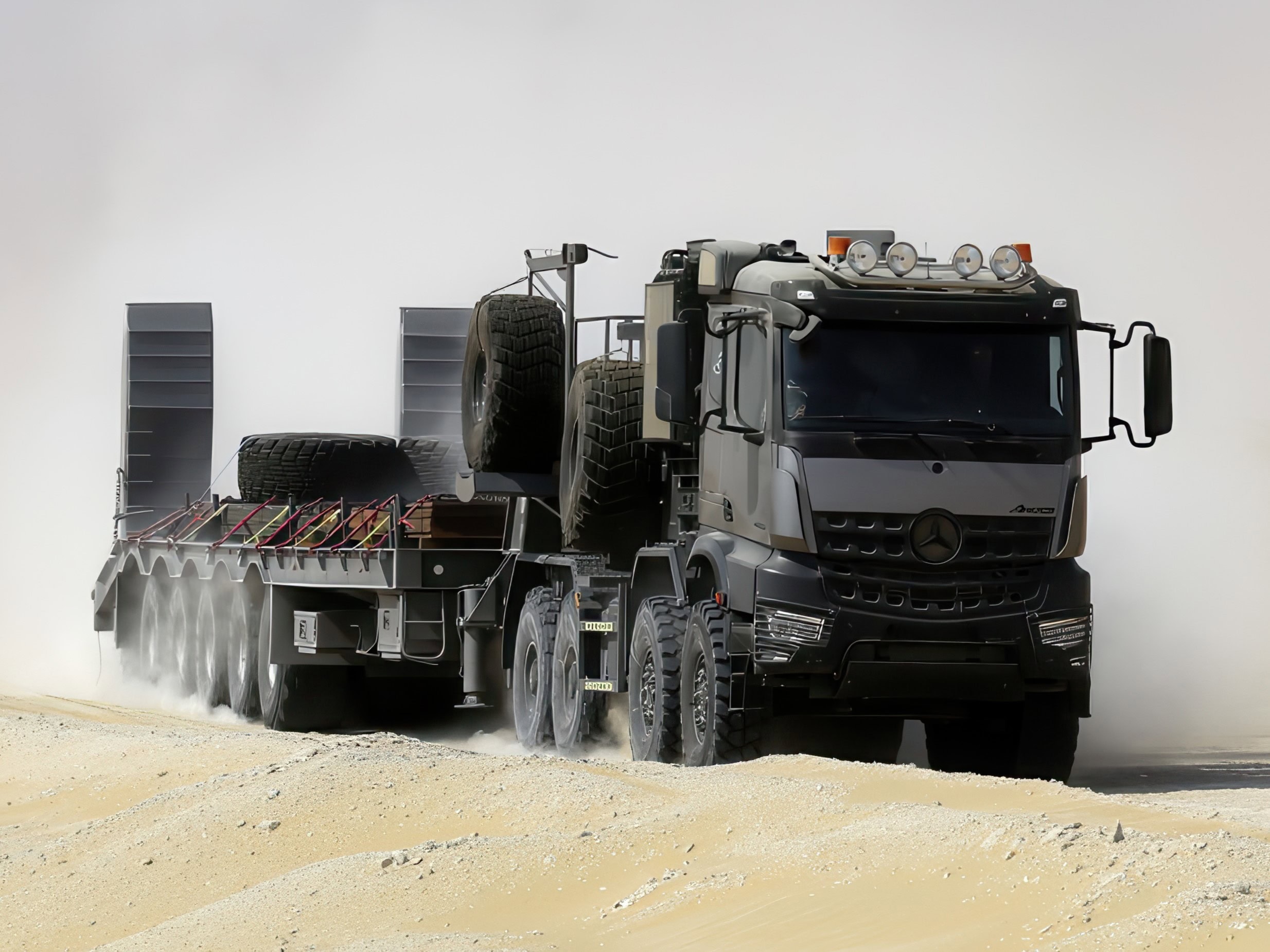 Eine Schwerlastzugmaschine vom Typ Mercedes-Benz Arocs 4663 AS 8x8 zieht einen Tieflader durch eine Wüstenlandschaft