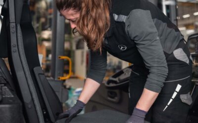 Eine Monteurin befestigt in einem Econic-Fahrerhaus eine Sitzfläche aus Recyclingmaterialien