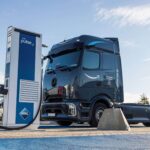 Eine batterieelektrische Sattelzugmaschine vom Typ Mercedes-Benz eActros 600 mit Aufschrift „Servicepartner von Amazon“ an der Seite steht an einer Megawatt-Ladesäule von Aral pulse