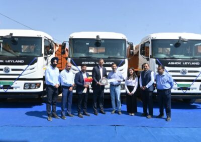 Ashok Leyland: Schwere E-Lkw mit "Dual Gun Charging" Eine Personengruppe mit Mitarbeitern von Ashok Leyland und ASAT Logistics vor drei schweren E-Lkw