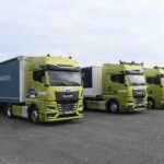 Vier Prototypen autonom fahrender Sattelzüge auf Basis MAN nebeneinander auf einem Parkplatz