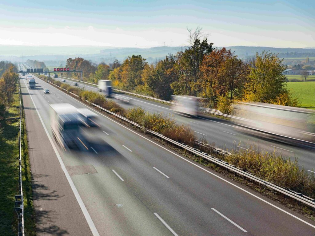 Blick auf eine bundesdeutsche Autobahn mit fließendem Verkehr von schräg oben, wobei in der Langzeitbelichtung die Fahrzeuge nur schemenhaft zu erkennen sind