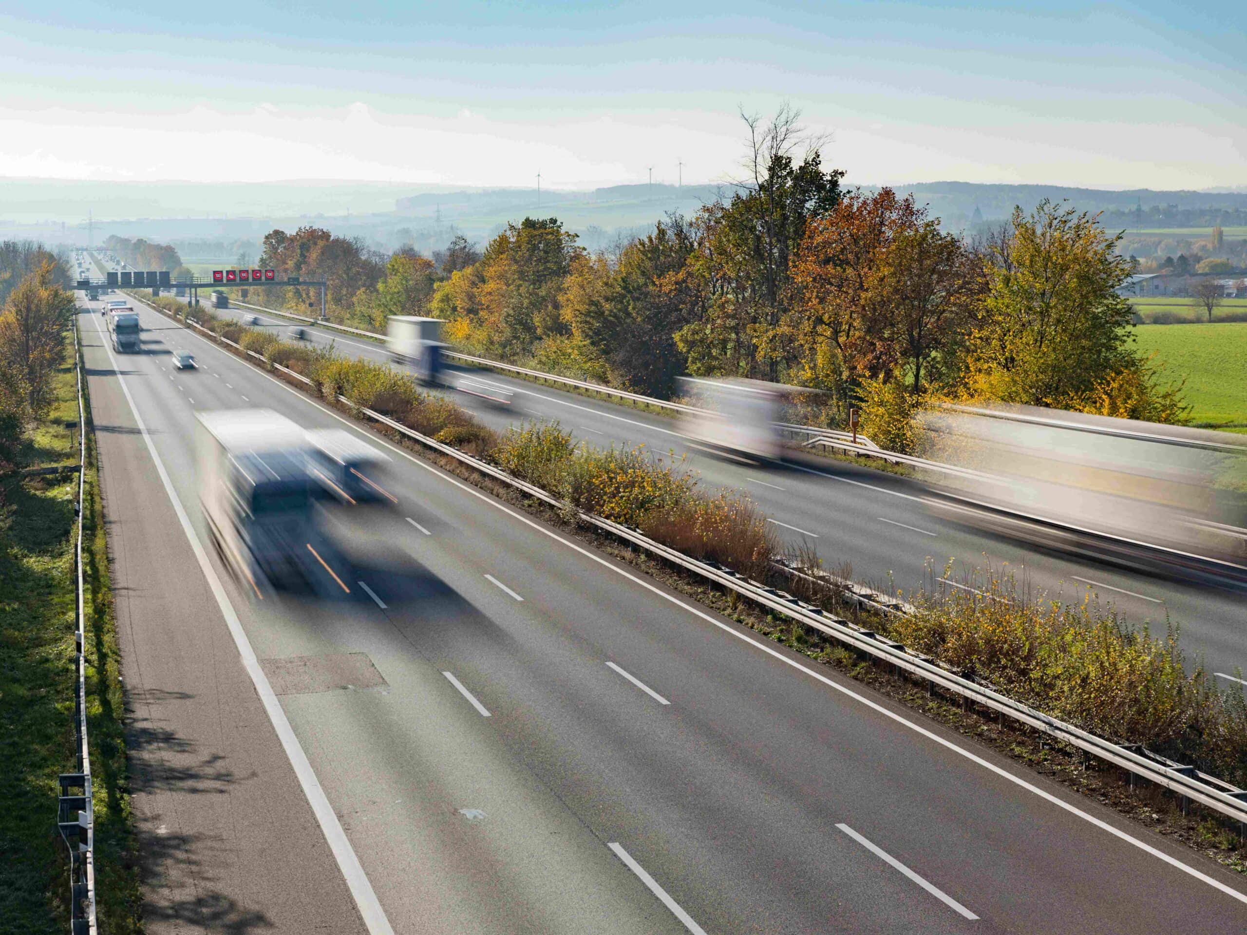 Blick auf eine bundesdeutsche Autobahn mit fließendem Verkehr von schräg oben, wobei in der Langzeitbelichtung die Fahrzeuge nur schemenhaft zu erkennen sind