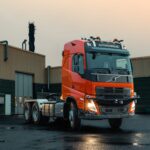 Eine autonom fahrende Dreiachs-Sattelzugmaschine auf Volvo-Basis, abgesattelt bei Dämmerung vor einer Halle