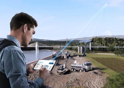 Ein Mann hält ein Tablet mit installierter Software von Bosch in der Hand, im Hintergrund Lkw und Baumaschinen