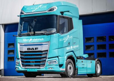 DAF: Produktionsstart für XG und XG+ Electric Eine batterieelektrische Sattelzugmaschine vom Typ DAF XG+ Electric in den Firmenfarben von Hellmold & Plank steht vor einem geschlossenen Hallentor