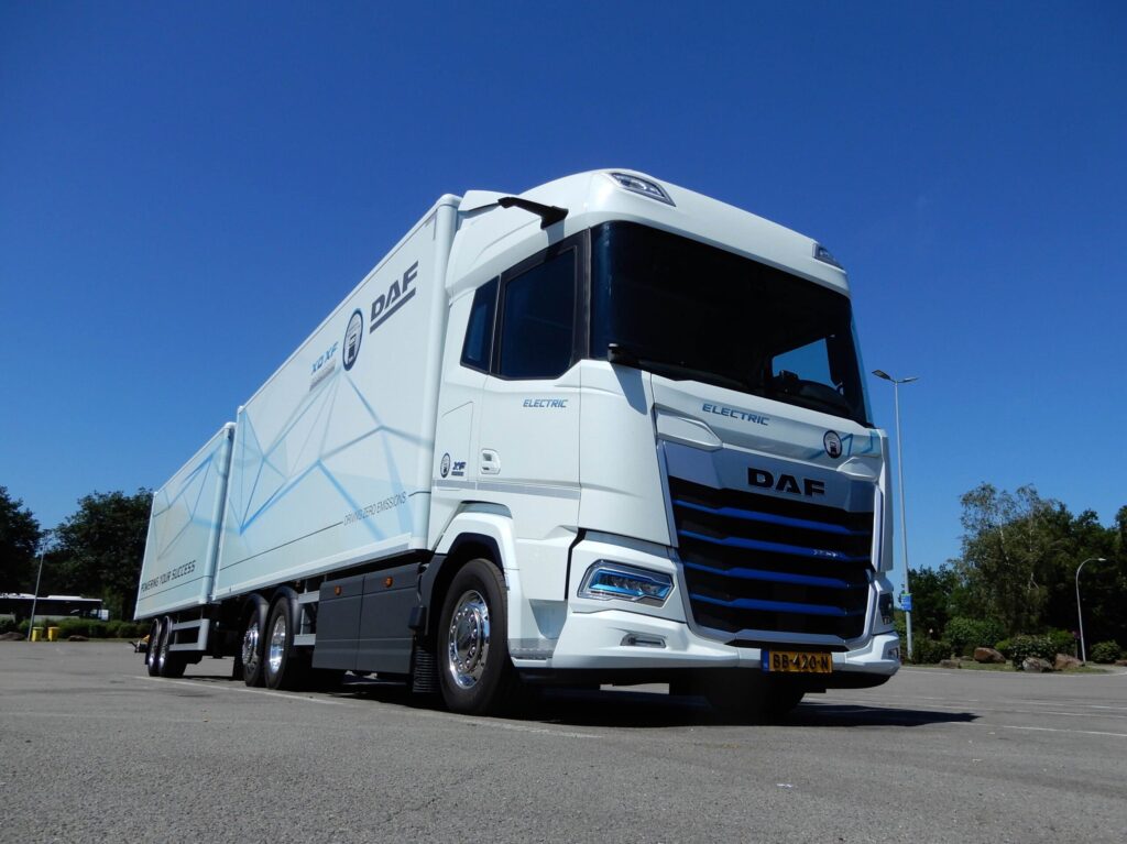 Ein Gliederzug mit einem batterieelektrischen DAF XF 350 FAN Electric 6x2 Sleeper High Cab auf einem Parkplatz