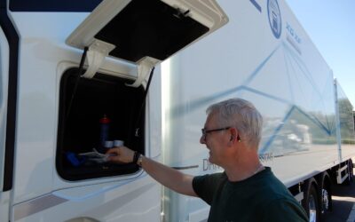 Blick auf das fahrerseitige Außenstaufach an einem batterieelektrischen DAF XF 350 FAN Electric 6x2 Sleeper High Cab; ein Fahrer legt ein paar Handschuhe hinein