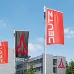 Blick auf die Hauptverwaltung der Deutz AG in Köln-Porz, im Vordergrund wehen Fahnen mit dem neuen Unternehmenslogo