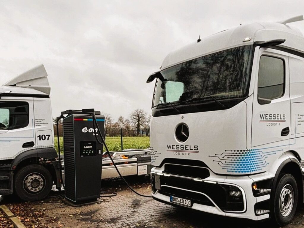Zwei Elektro-Lkw von Wessels Logistik laden an einer Ladesäule von E.ON