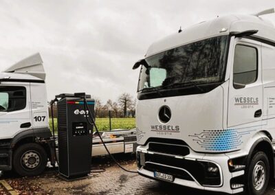 Zwei Elektro-Lkw von Wessels Logistik laden an einer Ladesäule von E.ON
