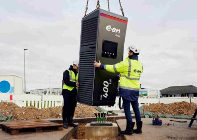E.ON und Tank & Rast erhalten Zuschlag für Megawatt-Ladenetz Zwei Arbeiter positionieren eine E-Lkw-Ladesäule, die von oben an Ketten herabgelassen wird