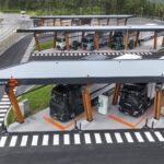 Ein Ladepark für Elektro-Lkw von Milence von schräg oben; es sind insgesamt fünf Lastzüge an Ladesäulen zu sehen