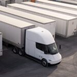 Eine batterieelektrische Sattelzugmaschine vom Typ Tesla Semi auf einem Terminalgelände mit zahlreichen abgestellten Sattelaufliegern