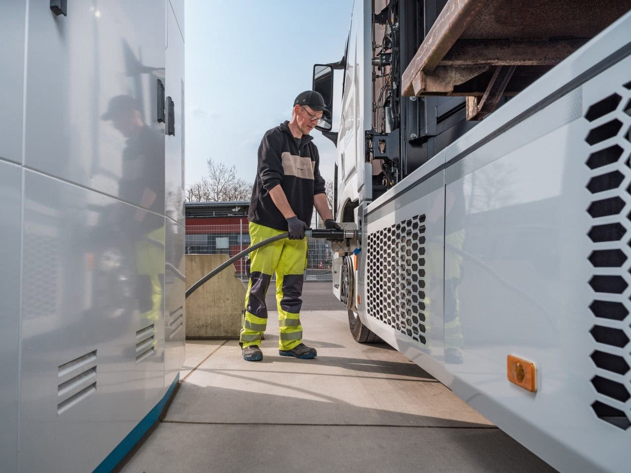 Ein Mann betankt an einer Wasserstofftankstelle einen Lkw