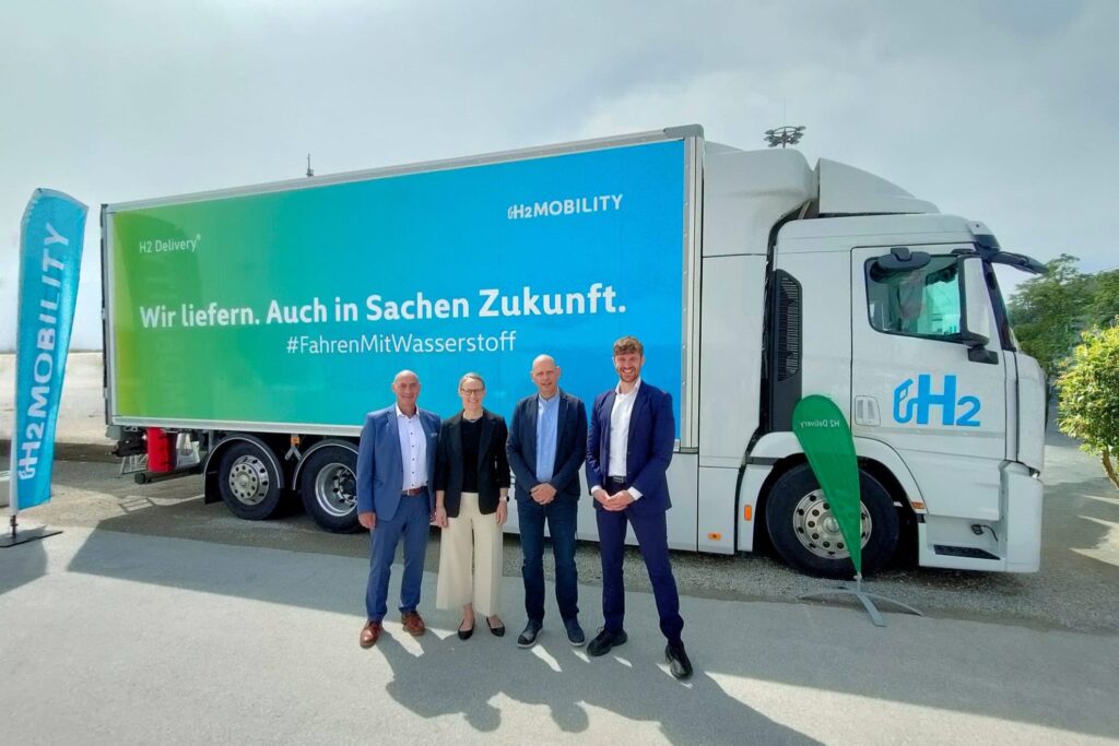 Gruppenbild von vier Personen vor einem Brennstoffzellen-Lkw