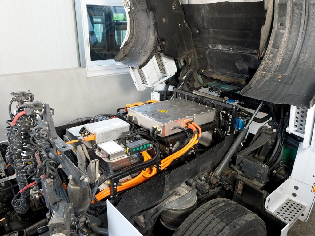Blick unter das Fahrerhaus eines zum BEV umgerüsteten Lkw mit E-Motor und Leistungselektronik
