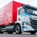 Ein dreiachsiger E-Lkw vom Typ Iveco S-eWay mit aufgebautem Wechselrahmen und Wechselbrücke von Gruber Logistics auf einem Parkplatz