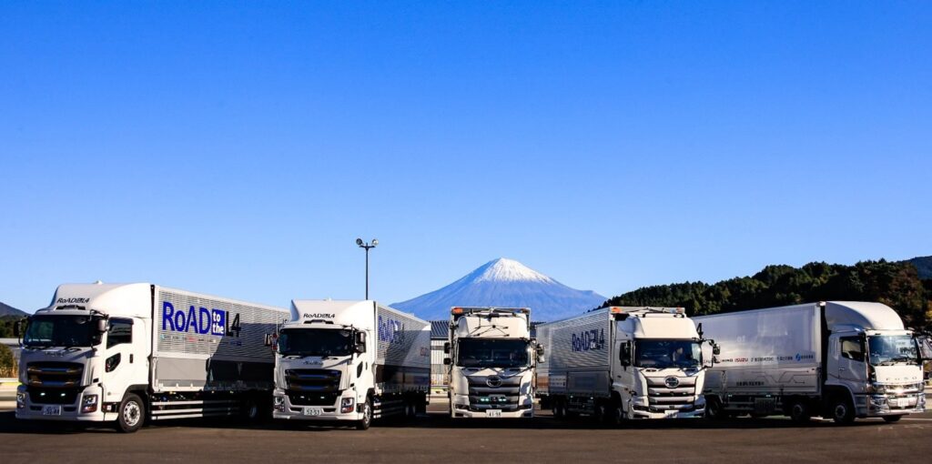 Vier schwere Lkw verschiedener japanischer Marken auf einem Parkplatz