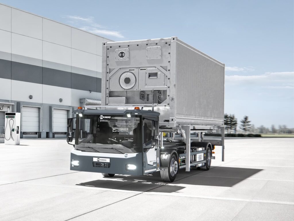 Ein batterieelektrischer Wechselbrückenumsetzer Kamag ePM 101 transportiert auf einem Betriebshof eine Wechselbrücke