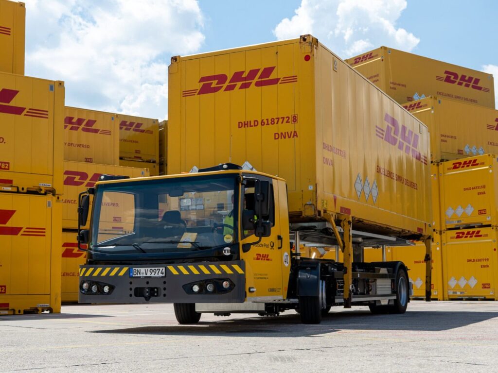 Ein elektrisch betriebener Wechselbrückenumsetzer vom Typ Kamag ePM, beladen mit einer Wechselbrücke im Design von Deutsche Post DHL Group