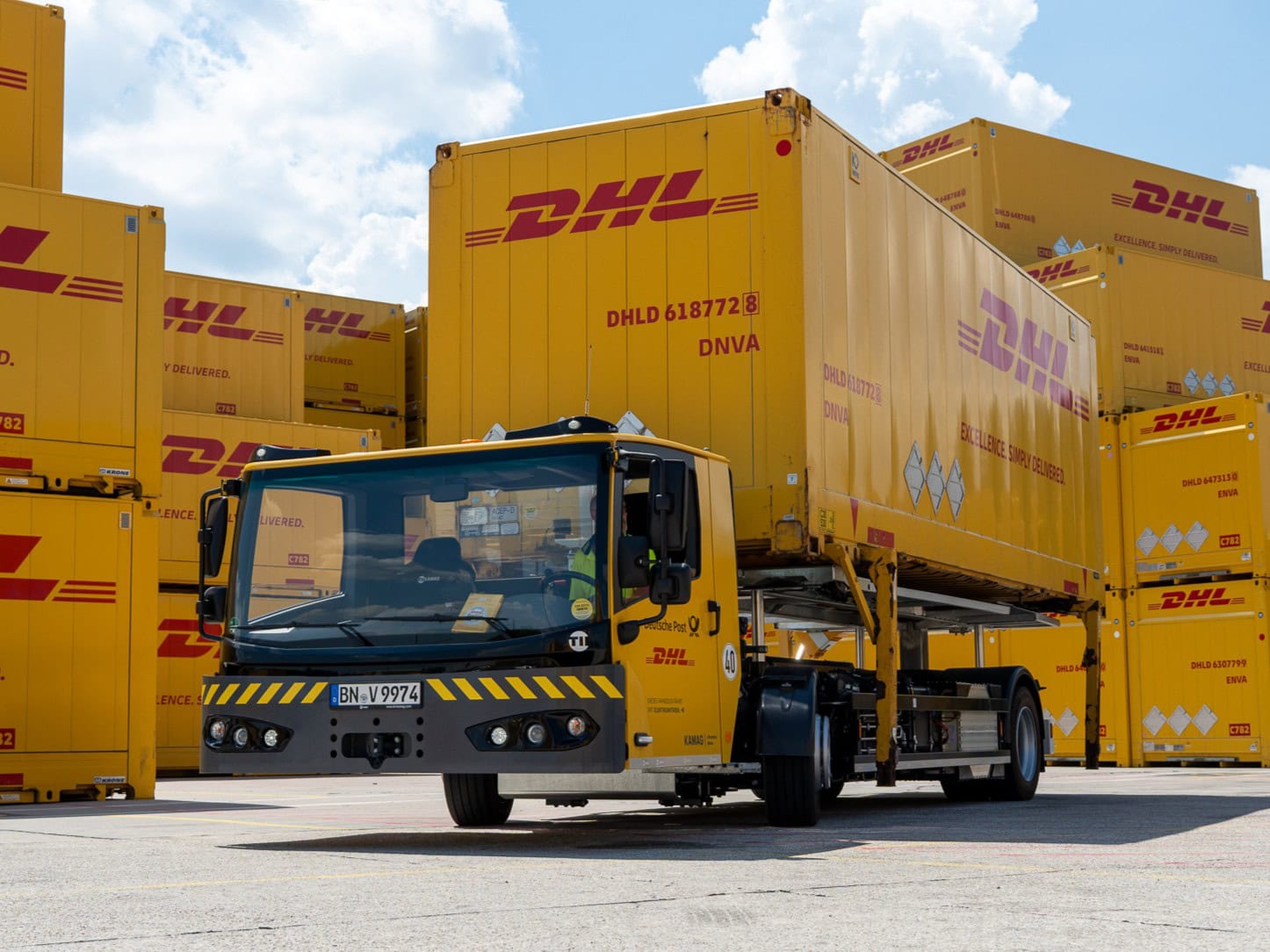 Ein elektrisch betriebener Wechselbrückenumsetzer vom Typ Kamag ePM, beladen mit einer Wechselbrücke im Design von Deutsche Post DHL Group