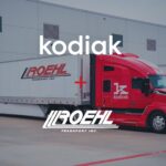 Ein Sattelzug von US-Logistiker Roehl Transport an einer Rampe; die Zugmaschine ist mit dem autonomen Fahrsystem „Kodiak Driver“ ausgestattet; über dem Bild liegen die Schriftzüge von Kodia und Roehl Transport