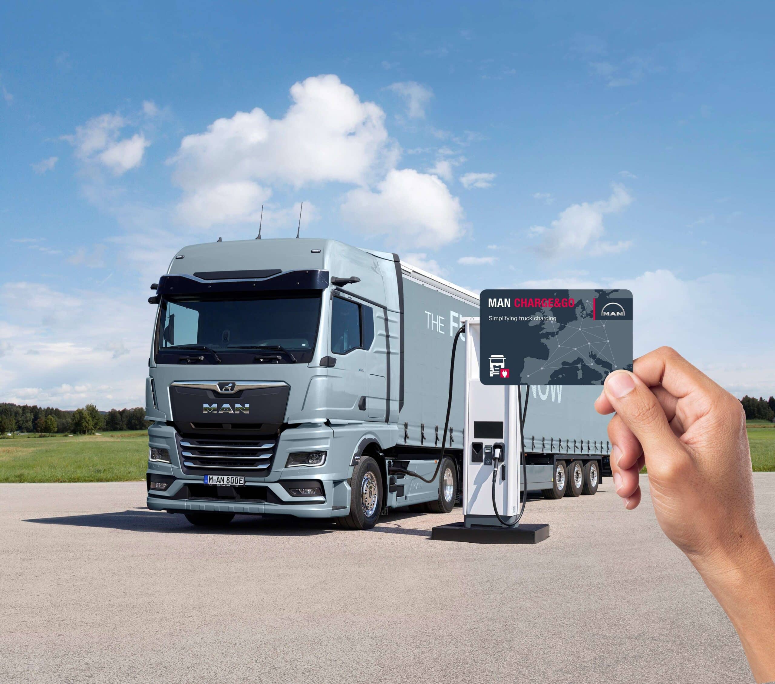 MAN eTGX an Elektro-Ladesäule, im Vordergrund eine Hand mit Charge & Go-Bezahlkarte