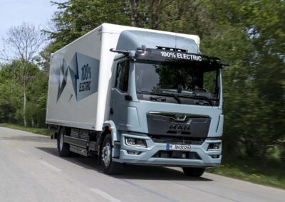 Ein batterieelektrischer Lkw vom Typ MAN eTGM mit Kofferaufbau auf einer Landstraße; Zweiachser