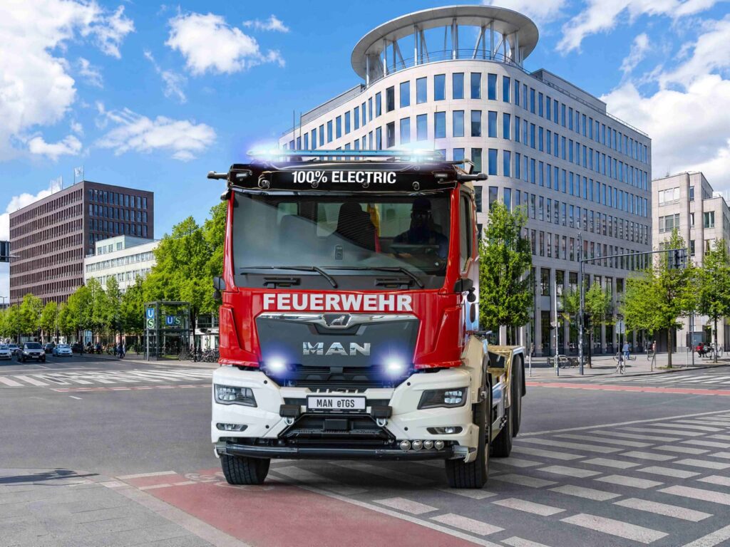 Der erste batterieelektrische MAN eTGS für die Feuerwehr, ein Dreiachser als Wechsellader mit Aufbau von Meiller vor städtischer Kulisse