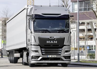 Ein Sattelzug mit einem MAN TGX auf einer innerstädtischen Straße; die Sattelzugmaschine ist mit dem System Optiview Basic ausgestattet, eine Kombination aus Kameras statt der Rückspiegel und einem konventionellen Frontspiegel