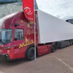 Sattelzug mit Kühlauflieger und Sattelzugmaschine MAZ-545000 mit Niederflurfahrerhaus und dieselelektrischem Antrieb auf einem Messestand im Freien