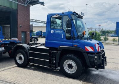 Ein batterieelektrischer ET400 von Orten Electric Trucks auf Unimog-Basis steht auf einem Betriebshof vor einer Halle