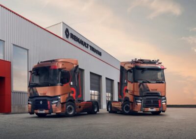 Zwei Sattelzugmaschinen von Renault Trucks solo vor einem Werkstattgebäude; links mit T-Fahrerhaus, rechts das höhere T High