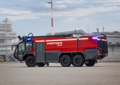 Rosenbauer mit Rekordjahr 2025 Flughafenlöschfahrzeug vom Typ Rosenbauer Panther Electric vor einem schemenhaft dargestellten Flughafen
