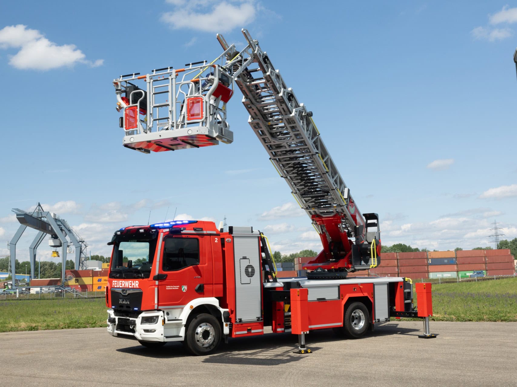 Drehleiterfahrzeug für die Feuerwehr auf einer Stellfläche, Stützen und Rettungskorb sind ausgefahren; es ist ein vollelektrisches Fahrzeug mit Aufbau von Rosenbauer auf einem MAN eTGM