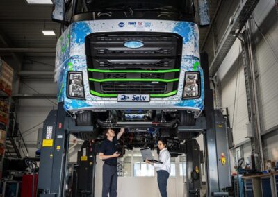 Ein schwerer Elektro-Lkw aus dem Projekt „SeLv“ auf einer Hebebühne, darunter ein Mann und eine Frau mit Messgeräten und Laptop