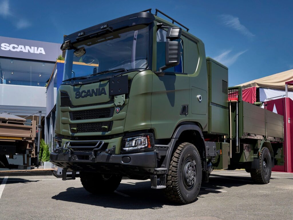 Zweiachsiger Hybrid-Lkw von Scania in Militärlackierung auf einem Messestand