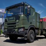 Zweiachsiger Hybrid-Lkw von Scania in Militärlackierung auf einem Messestand
