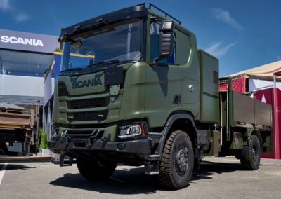 Zweiachsiger Hybrid-Lkw von Scania in Militärlackierung auf einem Messestand