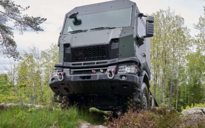 Ein Scania-Lkw mit militärischer Tarnung und gepanzertem Fahrerhaus auf einem unbefestigten Waldweg