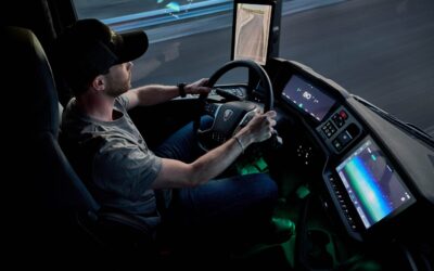 Blick auf das Cockpit mit Fahrer in einem neuen Scania-Lkw mit Spiegelersatzsystem und Monitoren an den A-Säulen; Nachtfahrt mit gedämmtem Licht im Innenraum