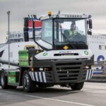Batterieelektrischer Terminal-Traktor von Terberg, Typ RT253EV 4x4, solo auf einer Hafenstraße; im Hintergrund ein Fährschiff
