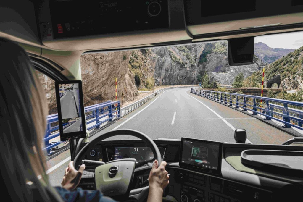 Innenansicht eines Volvo-Lkw mit Fahrerin, Blick durch die Windschutzscheibe auf die Straße