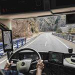Innenansicht eines Volvo-Lkw mit Fahrerin, Blick durch die Windschutzscheibe auf die Straße